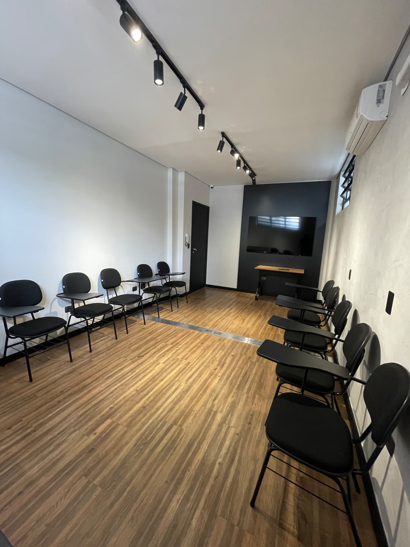 Sala de treinamento com cadeiras universitárias de frente para a TV no Tower Coworking em São Caetano do Sul